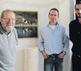 Drei Kunstschaffende, drei Quereinsteiger: Peter Huggenberger, Josef Häfliger und Gezim «Jimmy» Ristemi stehen vor zwei Werken der Ausstellenden. (Bild: rc.)