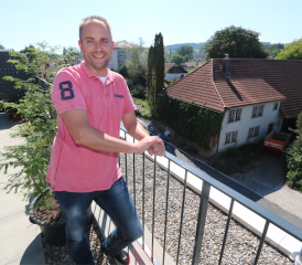 Neu und alt nahe bei einander, dazwischen Christian Schweizer. Der Menziker sieht von seiner Terasse an der Risistrasse aus direkt auf sein nächstes Projekt an dieser Stelle. Das alte Bauernhaus (rechts) steht derzeit im Rückbau. (Bild: Remo Conoci))