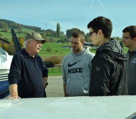 Der Pilot, Kurt Strittmatter, erklärt seinen Passagieren das Flugzeug