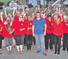 Nahmen den Dorfpfarrer in ihre Mitte: David Scherler in lockerem Outfit mitten unter der Uerkner Musikgesellschaft. (Bild: aw.)