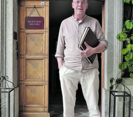 Gastgeber Thomas Wiederkehr vor dem Eingang des Huus 74 mit zwei Fotobüchern aus seiner Kindheit und Jugendzeit. (Bild: René Fuchs)