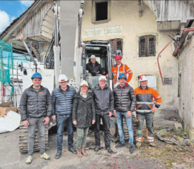 Gemeindeammann Peter Stadler sitzt im Bagger. Im Vordergrund sind der Trienger Frohsinn-Besitzer und Bauunternehmer Jules Steiger (2. von rechts) und der zukünftige Gemeindeammann Irene Bärtschi (Mitte) zu sehen, flankiert von weiteren Behörden- und Firmenvertretern. (Bild: Kaspar Flückiger)