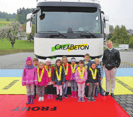 «Totwinkel»-Schulung: Die Kindergruppe eines Rickenbacher Kindergartens vor dem LKW, wo die mittels Spiegel einsehbaren Flächen mit Blachen markiert sind. (Bild: zVg.)