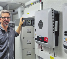 Projektleiter Roland Wüthrich im Technikraum mit Wechselrichter, Batteriespeicher und Warmwasser-Speicher