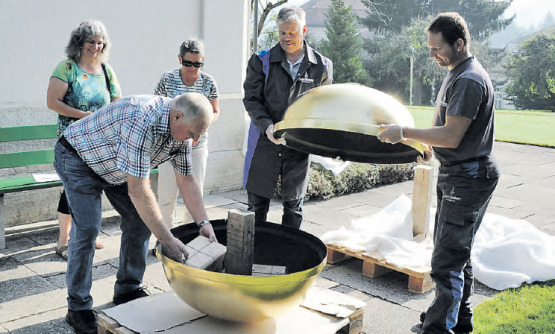 Kirchenpflegepräsident Arnold Schori (links) und die Kirchenpflegerinnen Elisabeth Perrinjaquet (hinten rechts) und Ruth Steiner legen Zeitzeugen zurück in die Kugel.