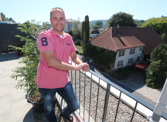 Neu und alt nahe bei einander, dazwischen Christian Schweizer. Der Menziker sieht von seiner Terasse an der Risistrasse aus direkt auf sein nächstes Projekt an dieser Stelle. Das alte Bauernhaus (rechts) steht derzeit im Rückbau. (Bild: Remo Conoci))