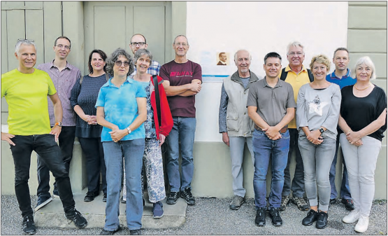 Die Wandergruppe bei der Erstbegehung des Barth-Thurneysen-Wegs: Vor der Tafel am Wöschhüsli neben der reformierten Kirche Uerkheim, neben der Tafel links die Gruppe von der Landeskirche und der Kirchgemeinde Safenwil mit Kirchenratspräsident Christoph Weber-Berg (li.) und Raffael Sommerhalder (hinten vor der Tür) und rechts die Gruppe aus der Kirchgemeinde Uerkheim. (Bild: zVg.)