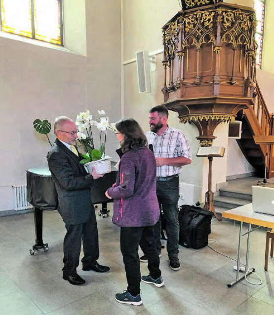 Feierlicher Akt: Jolanda Furrer, Sekrätärin der Kirchgemeinde, überreicht Pfarrer Andreas Schindler Blumen, rechts Präsident Roland Lörtscher. (Bild: zVg.)