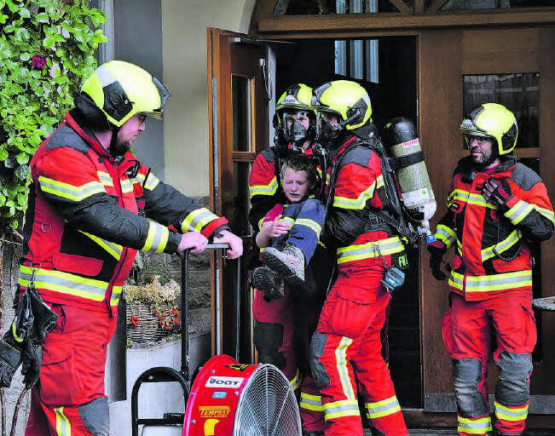 Fast unversehrt gerettet: Mit Gasmasken geschützt holten die Feuerwehrleute diesen Jungen aus dem Treppenhaus. (Bild: st.)