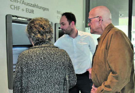 Kundenberatung vor Ort: Enrico Tiziani erklärt einem Ehepaar im Detail und mit Beispielen, was der neue Bancomat alles kann. (Bild: st.)