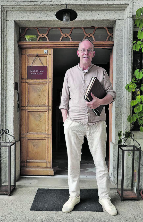 Gastgeber Thomas Wiederkehr vor dem Eingang des Huus 74 mit zwei Fotobüchern aus seiner Kindheit und Jugendzeit. (Bild: René Fuchs)