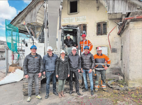 Gemeindeammann Peter Stadler sitzt im Bagger. Im Vordergrund sind der Trienger Frohsinn-Besitzer und Bauunternehmer Jules Steiger (2. von rechts) und der zukünftige Gemeindeammann Irene Bärtschi (Mitte) zu sehen, flankiert von weiteren Behörden- und Firmenvertretern. (Bild: Kaspar Flückiger)