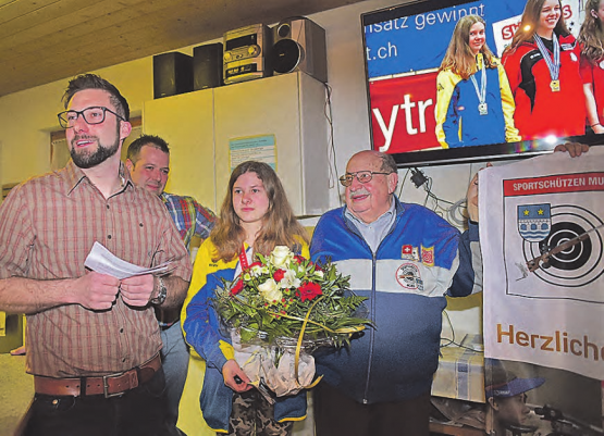 Sportliches Jubiläumsgeschenk: Präsident Daniel Berchtold (links) würdigte den Schweizer Juniorinnen-Meistertitel 10 m der Gewehrschützin Marion Obrist zu Beginn der Versammlung, rechts der langjährige Schulsportleiter Geri Künzli, hinten Schützenmeister Simon Hediger. (Bilder: wr)