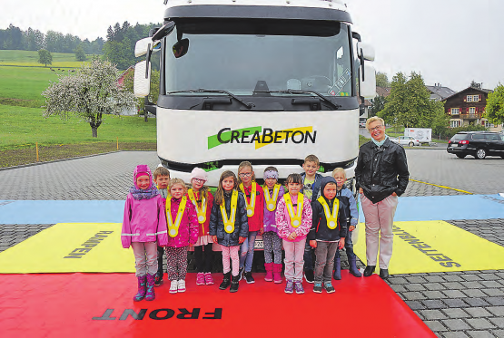 «Totwinkel»-Schulung: Die Kindergruppe eines Rickenbacher Kindergartens vor dem LKW, wo die mittels Spiegel einsehbaren Flächen mit Blachen markiert sind. (Bild: zVg.)