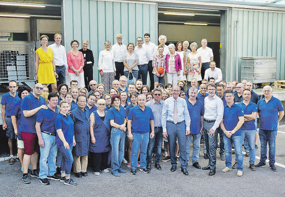 Gruppenfoto der Fretz Men AG: Hinten: Familienaktionäre,Angehörige und Verwaltungsräte der Fretz Men AG.Vorne: Jürg Schärer umgeben von der Belegschaft und der Geschäftsleitung mit den Herren Daniel Omlin (re.) und Walter Valenti (li.). (Bild: zVg.)