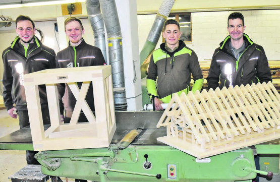 Zwei Lehrlinge im zweiten und dritten Lehrjahr präsentieren ihre prämierten Arbeiten: Lukas Hochuli einen Strebenwürfel, Janis Bossard einen Dachstuhl, Lehrlingsbetreuer Stefan Hofmann (l.) und Geschäftsführer Martin Hochuli (r.). (Bild: aw.)