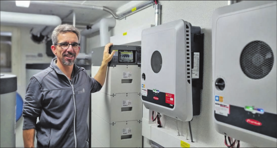 Projektleiter Roland Wüthrich im Technikraum mit Wechselrichter, Batteriespeicher und Warmwasser-Speicher